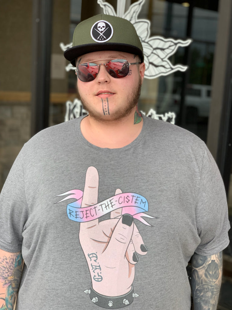 T-shirt with reject the cistem image in trans flag colours. In grey. Worn by trans artist Kristofer Woods.